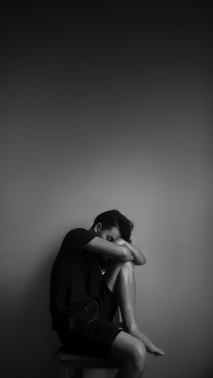 A black and white portrait of a man sitting alone, evoking emotion and contemplation.